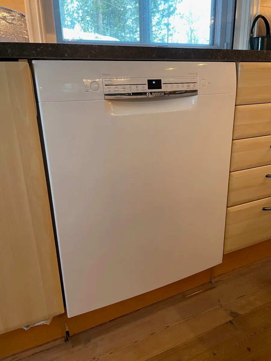 Hvit Bosch oppvaskmaskin under kjøkkenbenken, med kontrollpanel på toppen av døren