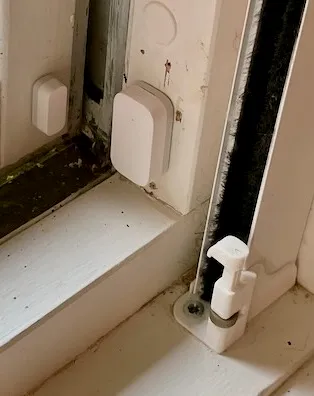 Hvit Aqara vindussensor i to deler, den ene på vinduskarmen og den andre på vindusrammen