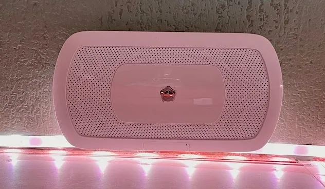 Hvit Verisure sirene på veggen rett over en lysstripe som lyser rosa