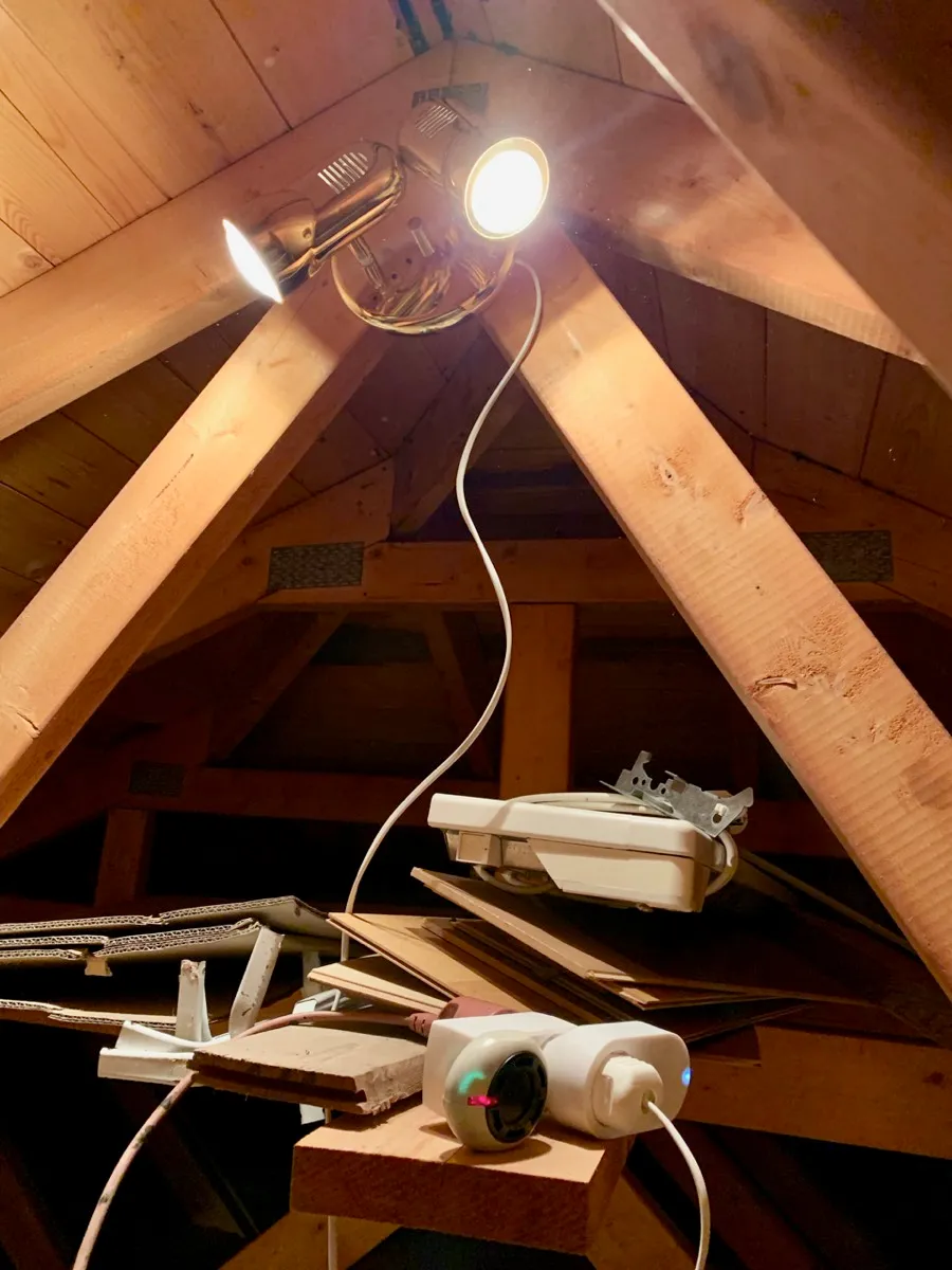 To spotlighter montert under mønet, med ledningen ned til en smartplugg på en hylle