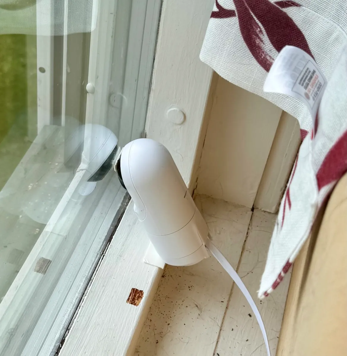 Lite hvitt UniFi-kamera i vinduskarmen, med linsen inntil glasset