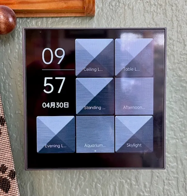 Aqara smart lysbryter på veggen, med klokke og syv knapper på skjermen, blant annet for taklys, bordlampe og kveldslys