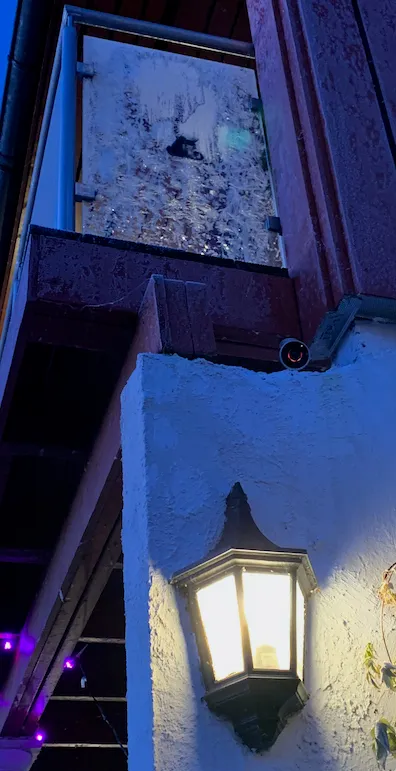 Lite rundt Logi Circle-kamera montert under verandaen, over en tent utelykt