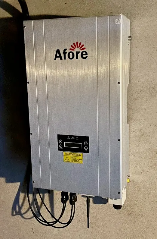 Grå Afore-inverter montert på en betongvegg, med kabler under